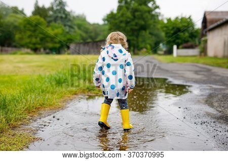 Little Toddler Girl Wearing Yellow Rain Boots, Running And Walking During Sleet On Rainy Cloudy Day.