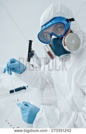 COVID-19. Doctor, microbiologist, scientist in a protective suit, makes a study of blood samples with coronavirus in the laboratory. 