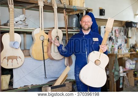 Successful Carpenter Posing Near Guitars That He Has Made In A Workshop