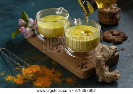 Two Cups Of Ayurvedic Drink Golden Milk Turmeric Latte With Curcuma Powder, Ginger And Honey Over Gr