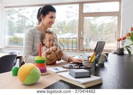 remote job, multi-tasking and family concept - happy smiling mother with baby and laptop working at home office