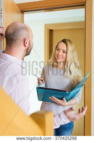 Man Answer Questions Of Outreach Worker With Paper In Home Door