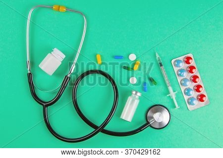 Studio Shot Of Stetoscope, Syringe And Pills On Light Green Background. Top Views.