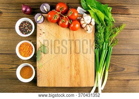 Wooden Board With Clear Space. Around Tomato And Dill, Olive Oil, Peper, Avocado, Green Onion, Spina