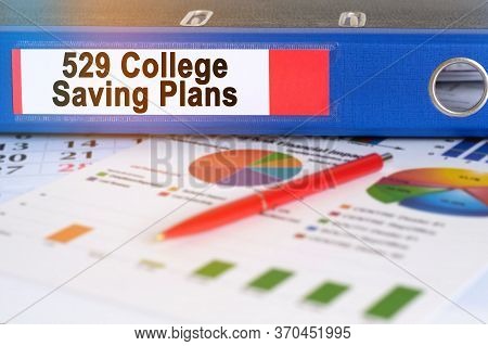 On The Table Are Pie Charts, A Pen And A Folder With The Inscription - 529 College Saving Plans. Bus