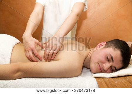 Man Procumbent With Hands Of Masseur With White Towels