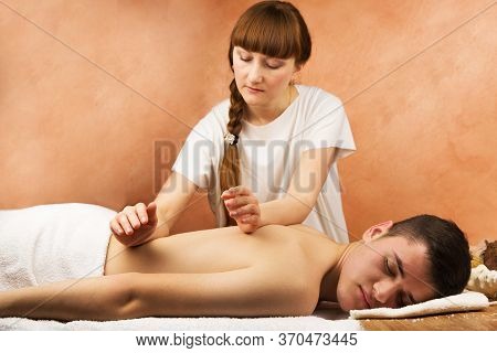 Man Procumbent With Hands Of Masseur With White Towels