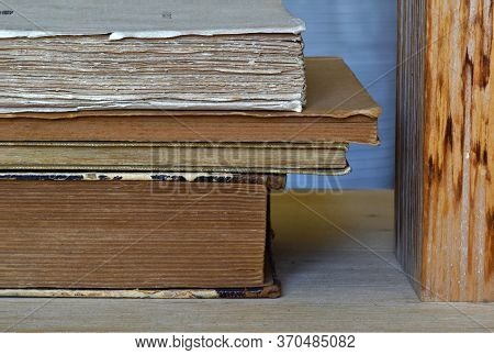 Old Books Messily Piled Up One On Top Of The Other Next To A Wooden Block