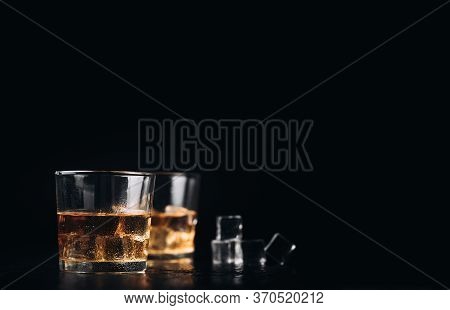 Whisky, Whiskey, Bourbon Or Cognac With Ice Cudes On Black Stone Table