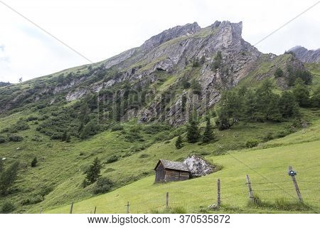 Wooden Tyrolean House On A Meadow Hill Surrounded By Rocky Mountains In The Fog In Austrian Alps Nea