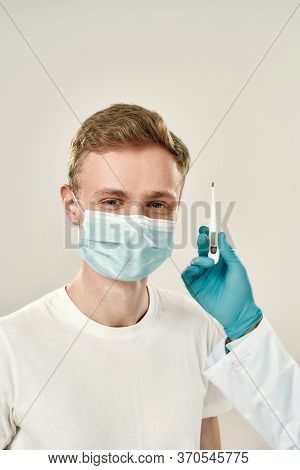 No Symptoms. Happy Young Man In Medical Protective Mask Smiling At Camera While Doctor In Blue Steri