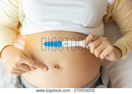 Happy Pregnant Woman Holding Pregnancy Test Pointing Finger To Beautiful Belly That Pregnant Girl Ha