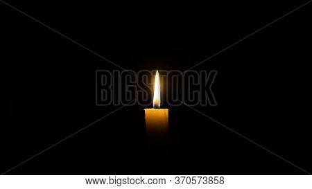 A Candle Burns In The Darkness, Copy Space. A Lit White Candle On A Black Background. Symbol Of Eter