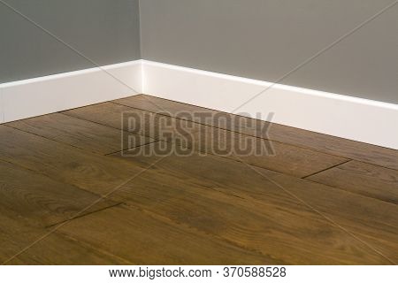 Close Up Of White Plastic Plinths On Dark Wooden Oak Floor Parquet.