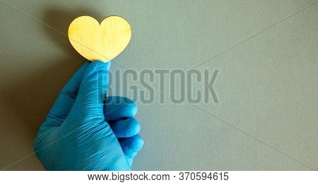 Wooden Heart, Hand In Blue Glove On Blue Background.