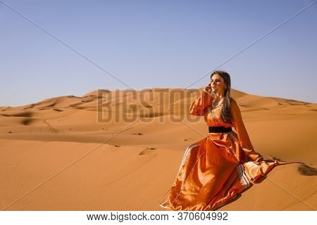 Beautiful Young Girl In Moroccan Dress In Sahara Desert.