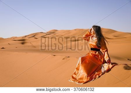 Beautiful Young Girl In Moroccan Dress In Sahara Desert.