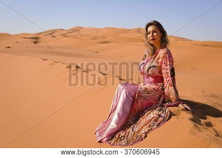 Girl In Moroccan Dress In Sahara Desert.
