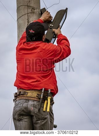 Workman Attaches Led Lgiht To Pole For Festival