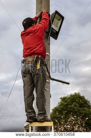 Workman Attaches Led Lgiht To Pole For Festival
