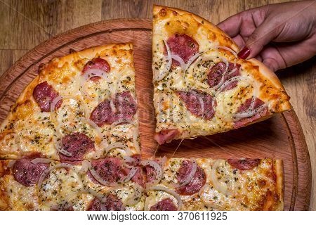 Hand Holding Pepperoni Pizza In Brazil Is Called Pizza De Calabresa. Close Up