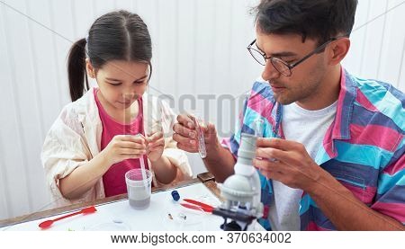Father And His Daughter Doing Science Experiments In The Laboratory. Dad And Little Girl Study Chemi