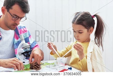Father And His Daughter Working And Exploring With The Microscop. Dad And Little Girl Study Chemistr
