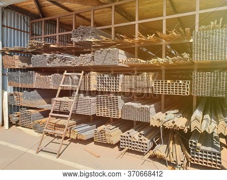 Construction Market. Racks With Metal Rods And Profiles With A Ladder Attached To Them