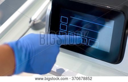 The Doctor Touches The Screen Of A Modern Device/ Close Up View Of Doktor's Hand In Blue Glove