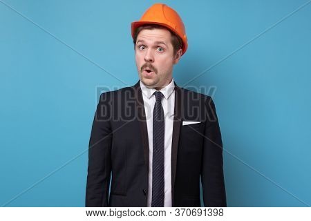 Construction Worker In Specia Hard Hat Is Shocked With News On Blue Background