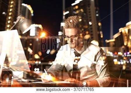 Double Exposure Of Young Man Working In Office And Night Cityscape. Financial Analytics