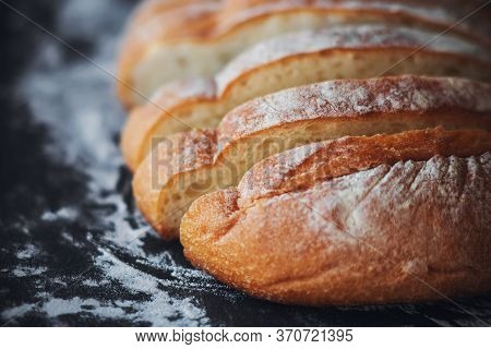 Fresh, Warm, Sliced Wheat Bread Lies On A Dark Baking Tray Strewn With White Crumbly Flour. Bakery P