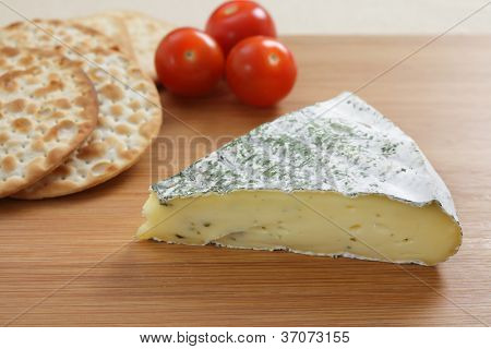 Eine Käseplatte mit einem herbed französischer Brie, Kekse und Tomaten.