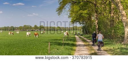Panorama Of A Couple Riding Their Bicycle At A Dirt Road In Overijssel, Netherlands
