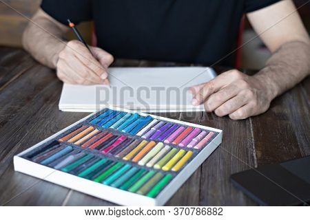 Person, Artist Painting With A Pastel Crayon Chalk On Sketchbook On The Wooden Table, Selective Focu