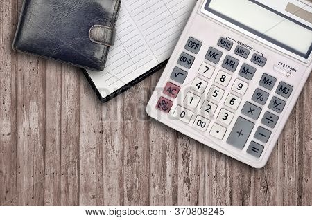 Office Flat Lay Composition With Calculator, Address Book And Black Purse On Brown Wooden Table Back