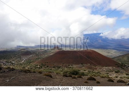 Scenic Mauna Kea Landscape With Paved Road To Summit Between Old Craters And View On Mauna Loa In Cl