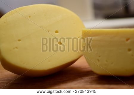Edam yellow cheese is located on a wooden board.