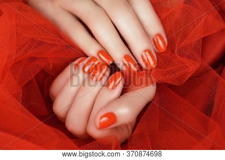Female Fingers With Bright Red Manicure On A Red Background