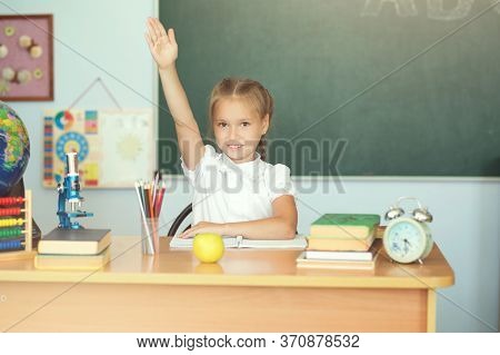 Cute Schoolgirl Pupil Raising Hand In Classroom