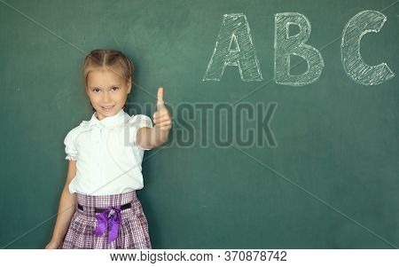 Portrait Of Caucasian Happy Child Girl With. School Chalkboard Or Blackboard Background. Education C