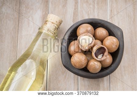 Nuts And Macadamia Oil On Wooden Background - Macadamia Integrifolia