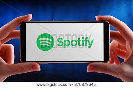 Hands Holding Smartphone Displaying Logo Of Spotify