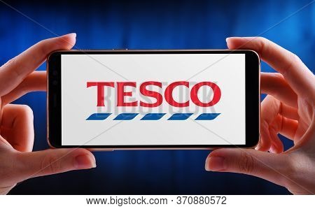 Poznan, Pol - May 21, 2020: Hands Holding Smartphone Displaying Logo Of Tesco, A Multinational Groce
