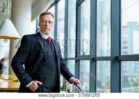 Senior Businessman Wears Modern Suir And White Shirt. Big Window With City View . Photo From The Sid