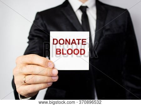 The Word Blood Donation Medical Concept Written In Red Letters On A White Piece Of Paper In The Hand