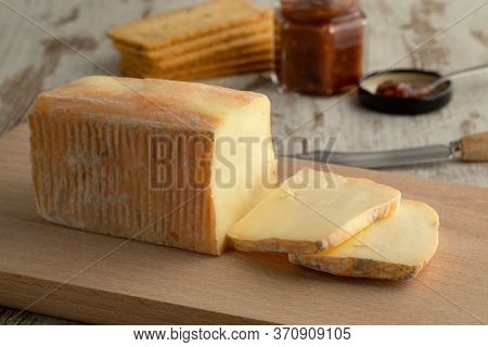 Piece and slices of traditional Italian Taleggio dop cheese close up on a cutting board