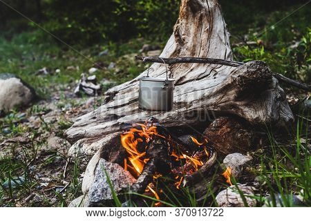 Kettle Hanging Over Fire. Cooking Food At Fire In Wild. Beautiful Big Log Burns In Bonfire Close-up.