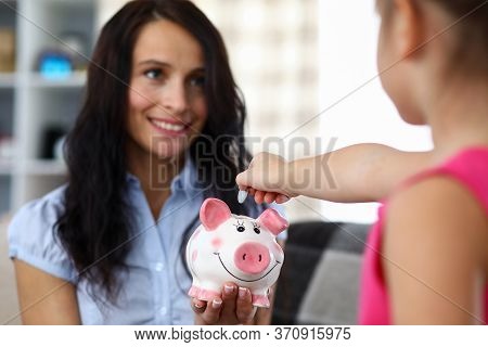 Portrait Of Happy Mother Holding Pink Funny Piggy Bank. Little Child Putting Money Into Thrift-box. 