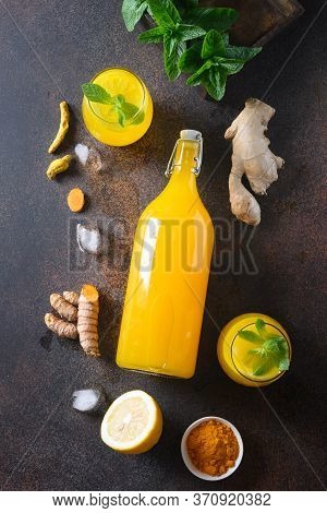 Jamu Indonesian Herbal Beverage In Bottle With Natural Ingredients Turmeric, Ginger On Brown Backgro